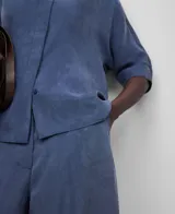 Camisa azul de lyocell, de corte holgado, con cuello mao, manga corta japonesa y botonadura frontal oculta.