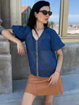 Camisa azul marino de gasa, con escote en V, mangas cortas abullonadas y detalle de piedras azules en el frente.