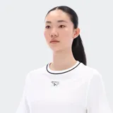Remera corta blanca de algodón con cuello redondo ribeteado en negro y logo Reebok bordado en el pecho.