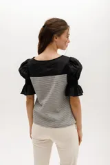 Blusa de rayas horizontales grises y blancas, con mangas abullonadas cortas negras y escote redondo.