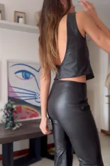 Pantalón Oxford negro de cuero sintético con cierre frontal y aberturas laterales con pasamanería plateada.