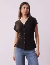 Remera blanca de lino, marca Zac & Rachel, con escote en V, abertura con botones y frunce en la parte delantera.