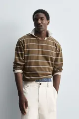 Camiseta marrón con rayas horizontales blancas y negras, de corte relaxed fit, cuello redondo amplio y mangas largas.