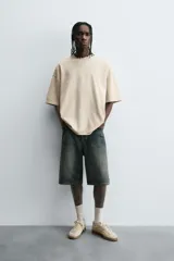 Camiseta color beige de corte holgado, cuello redondo y manga corta.