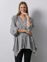 Camisa celeste de tencel, corte amplio, con cuello mao, escote en V y abotonadura frontal. Tiene bolsillos aplicados en el pecho, mangas 3/4 regulables con presilla y ruedo desflecado.