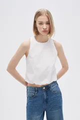 Blusa blanca de algodón sin mangas, con cuello a la base, abertura en la espalda y lazo ajustable.
