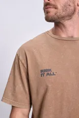 Remera marrón de corte oversize con estampa de estrellas y la frase "Risk It All. Write your own story" en la espalda.