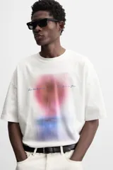 Camiseta blanca de corte relaxed fit, cuello redondo y manga corta. Estampado combinado a contraste en el delantero con imagen borrosa de flor y texto en azul.