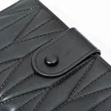 Billetera negra de simil cuero con diseño acolchado y cierre a presión.