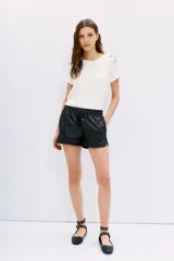 Short negro de cuero sintético con cintura elástica ajustable con cordón, bolsillos laterales y punteras metálicas.