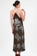 Top verde con estampado de figuras mitológicas en blanco y negro, escote en V con encaje negro y tirantes finos.