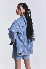 Campera de jean celeste con lavado ácido y estampado de estrellas blancas. Es de corte oversize.
