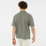 Camisa verde de manga corta con tejido calado, cuello clásico y bolsillo en el pecho.