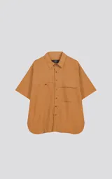 Camisa beige de manga corta con doble bolsillo ojal en delantero con solapa en uno de ellos, realizada en tejido plano, suave al tacto, silueta oversize.