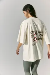 Remerón de jersey de algodón color crudo, de manga corta, con estampa en serigrafía en frente y espalda con la frase "co-creator of love & dreams" y un arco y flecha.