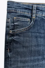 Jeans skinny de tiro alto en denim azul oscuro, con cinco bolsillos y cierre frontal con cremallera y botón metálico.