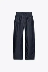 Pantalón de jean azul oscuro, de tiro alto, corte ancho y largo hasta el tobillo.