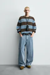 Pantalón de jean celeste de corte holgado y amplio en toda la pierna, tiro medio, tejido rígido, cinco bolsillos, efecto lavado, parche en trasero y bolsillo de vivo en pernera.