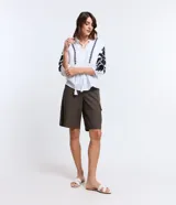 Blusa amplia de viscolino color blanco con bordados florales negros en mangas y escote, lazo en el cuello y mangas 3/4 con puño ajustado.