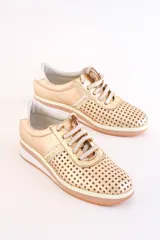 Zapatillas bajas doradas de cuero con diseño calado, cordones blancos y suela de goma.