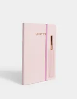Set de librería que incluye un cuaderno A5 forrado en PU rosa pastel con elástico y una lapicera metálica de tinta negra.