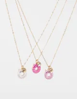 Set de 3 collares dorados para compartir con dijes esmaltados de dona: una blanca con confites de colores, una rosa con rayas y una rosa con forma de gato.