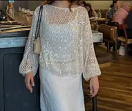 Blusa de fiesta color blanco, de mangas largas y tejido de red con lentejuelas.