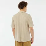 Camisa beige de manga corta con tejido calado, cuello clásico y cierre frontal con botones.