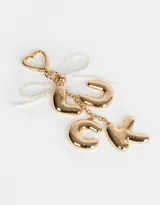 Llavero con dije de letras doradas que forman la palabra "LUCK" y cinta de perlas sintéticas.