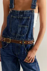 Overol de denim azul con tirantes ajustables, bolsillos frontales y traseros, y corte recto.