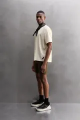 Camiseta deportiva marrón con estructura perforada, cuello redondo, manga corta y logo estampado.
