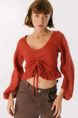 Blusa blanca de lino con escote en V, mangas largas abullonadas y frunce central.