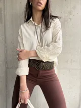 Camisa beige de manga larga con bordado floral en las mangas y cuello clásico.