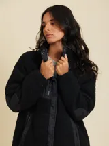 Campera de sherpa color negro con cierre frontal con botones a presión y bolsillos laterales.