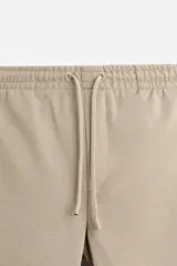 Pantalón negro de corte cropped, con cintura elástica ajustable con cordón, bolsillos laterales y traseros de vivo. El bajo tiene terminación con vuelta.