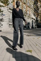 Jeans de tiro alto, corte recto y largo, color negro lavado, con abalorios brillantes distribuidos por toda la prenda.