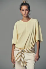 Camiseta color amarillo pastel de corte amplio, cuello redondo y mangas cortas.