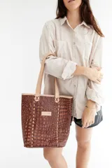 Bolso tipo tote de cuero marrón con textura de cocodrilo, doble asa corta y cierre superior.