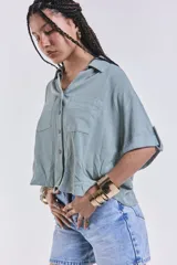 Camisa verde agua con cuello clásico, cierre frontal con botones, mangas cortas con dobladillo y dos bolsillos de parche en el pecho.