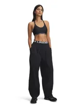 Top deportivo Under Armour modelo Crossback Low, color gris con logo en el elástico inferior.