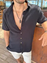 Camisa negra de algodón con textura waffle, corte clásico, cuello americano y botones color madera.