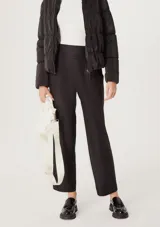 Pantalón negro de corte carrot con cintura alta y pinzas frontales.
