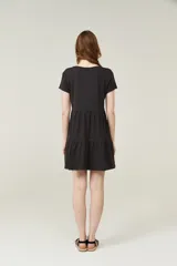 Vestido negro corto con cuello en V, manga corta y falda con volados.