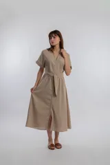 Vestido camisero midi color beige, con cuello camisero, mangas cortas con dobladillo, cierre frontal con botones y lazo para ajustar en la cintura.