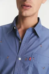 Camisa de manga larga azul con estampado de ciervos en color marrón. Tiene un bolsillo en el pecho y cierre con botones.