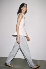 Pantalón de jean de tiro medio con pierna ancha y corte tapered, confeccionado en tejido de algodón revestido color gris claro. Cuenta con bolsillos delanteros y traseros, trabillas en la cintura y cierre frontal con cremallera y botón.