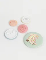 Set de cinco pines metálicos con diseños color pastel, incluyendo botas florales y mensajes inspiradores.