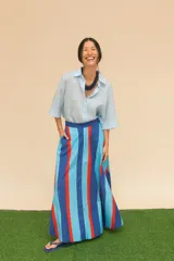 Pollera larga de algodón con rayas verticales en azul, celeste y rojo. Tiene cintura alta y bolsillos laterales.