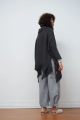 Poncho tejido de lana color gris oscuro, con cuello alto y flecos en el ruedo.