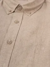 Camisa de manga larga azul, de lino y poliéster, con cuello abotonado y bolsillo en el pecho.